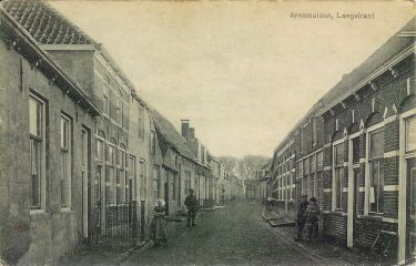 De Langstraat met aan de linker kant het doktershuis met de twee dakkapellen. Het eerste huis links is van timmermansbaas Jan Buis met daar tegenover zijn werkplaats.