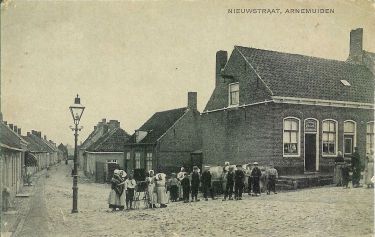 Op de hoek Nieuwstraat/Westdijkstraat de vroegere kruidenierswinkel van de familie Janse-Siereveld. Links in de Nieuwstraat bij het zonnescherm de bakkerswinkel van P. Minnaard (voorheen van bakker De Graag). Achteraan links in de Nieuwstraat de timmermanswinkel van De Hamer.