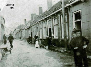 In de Westdijkstraat zien we de vrouwen druk bezig met de stoepen te schuren. Het schuren van de straten wordt dit jaar verboden.