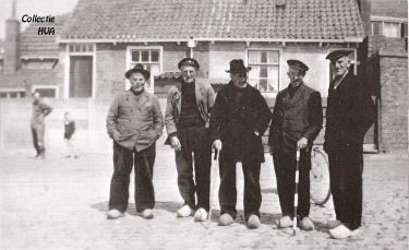 De oude vissers op de Zuidwal. Ze gaan een kijkje nemen bij de aan het Hoofd afgemeerde vissersschepen. V.l.n.r Klaas Marijs, Job Schroevers, Johannes Marijs, Klaas van de Ketterij en Adriaan Theune. Allen dragen witgeschuurde klompen. De meeste oude vissers dragen een visserspet, maar sommigen droegen een zwarte hoed.