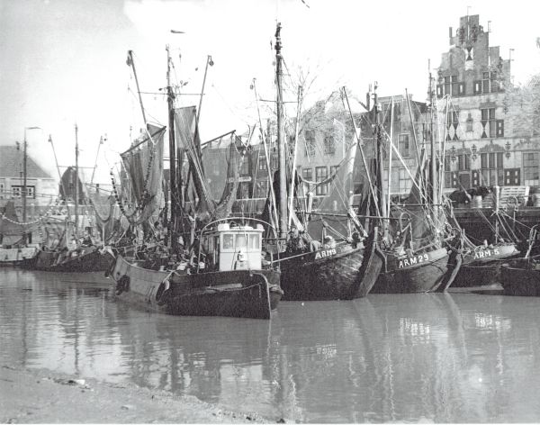 Wat een bonte bedrijvigheid in de vissershaven van Veere, voor de Schotse Huizen en links de vismijn. (Uit collectie Jhr. W.L. den Beer Poortugael).