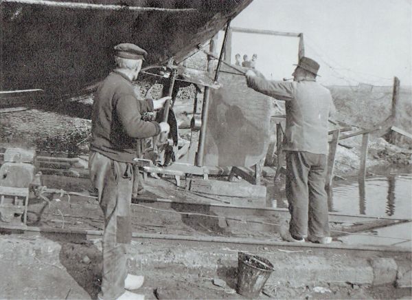 Op de werf is er altijd bedrijvigheid. Daar worden de vissersschepen opgekalefaterd of nieuwe hoogaarzen gebouwd. Hier wordt de romp geteerd. Vanaf het Schorretje kijkt de jeugd toe. (Uit collectie Jhr. W.L. den Beer Poortugael, Veere).