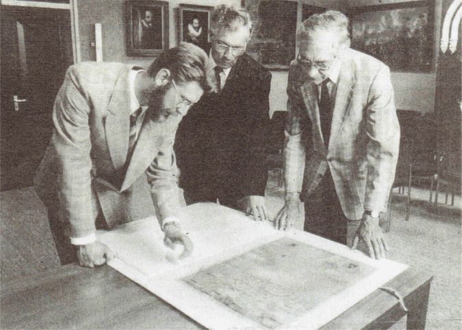 Burgemeester H. Visser (links), oud-gemeentesecretaris J. Kroon (midden) en Rabo-directeur M. Vader (rechts) bij de gerestaureerde 16e eeuwse kaart van Arnemuiden.