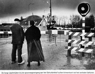 De lange wachttijden bij de spoorwegovergang op het Schuttershof zijn een ergernis voor de inwoners. H. Meulmeester en z'n vrouw, wonend aan het Schuttershof, staan hier geduldig te wachten.