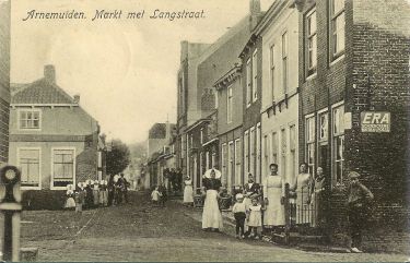 De Markt met aan het eind van de Koestraat de nieuwe gemeenteschool. Geheel rechts de winkel van Jacob Crucq. Met in de deuropening mevrouw Crucq-Kwekkeboom.